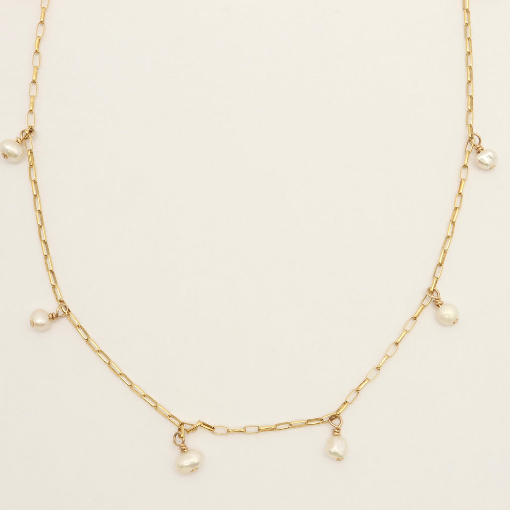 Gold necklace with pearls on a light beige background