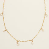 Gold necklace with pearls on a light beige background