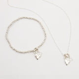 Silver heart pendant on fine silver beaded bracelet, featuring a clear Austrian crystal. Alongside matching necklace.