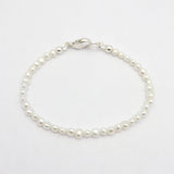 A delicate bracelet made of small white freshwater pearls linked with a polished silver clasp, displayed on a clean white background.