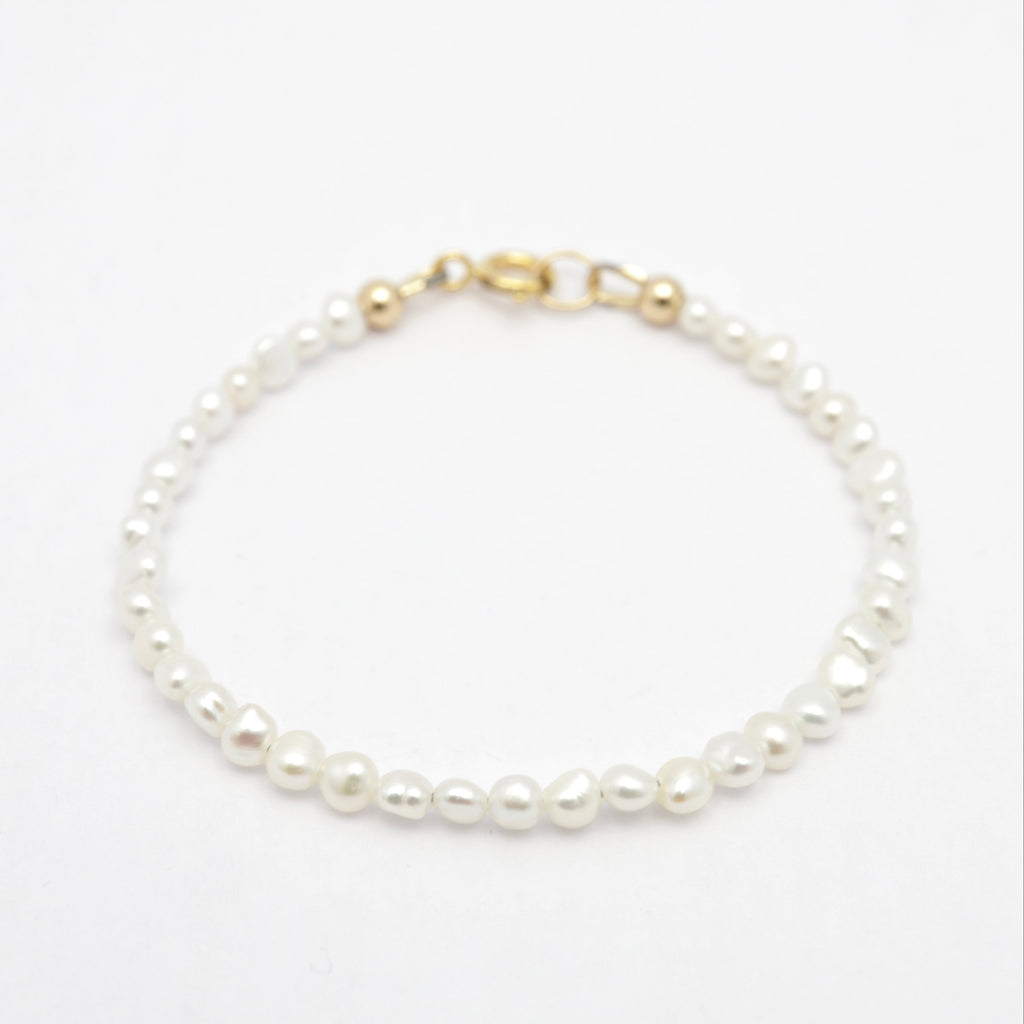 A delicate freshwater pearl bracelet with irregular white pearls and gold-filled clasp, displayed on a clean white background.