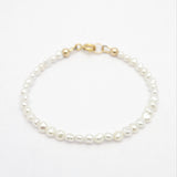A delicate freshwater pearl bracelet with irregular white pearls and gold-filled clasp, displayed on a clean white background.