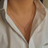 Gold necklace worn by a person wearing a white shirt