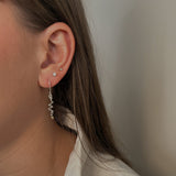 Close-up of a person wearing a silver spiral earring with a neutral background